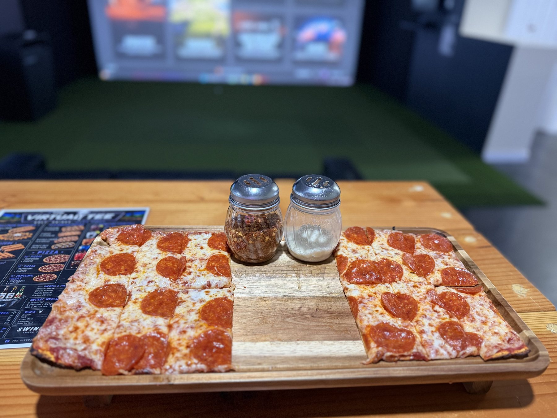 Pepperoni flatbread served beside a simulator bay at The Virtual Tee