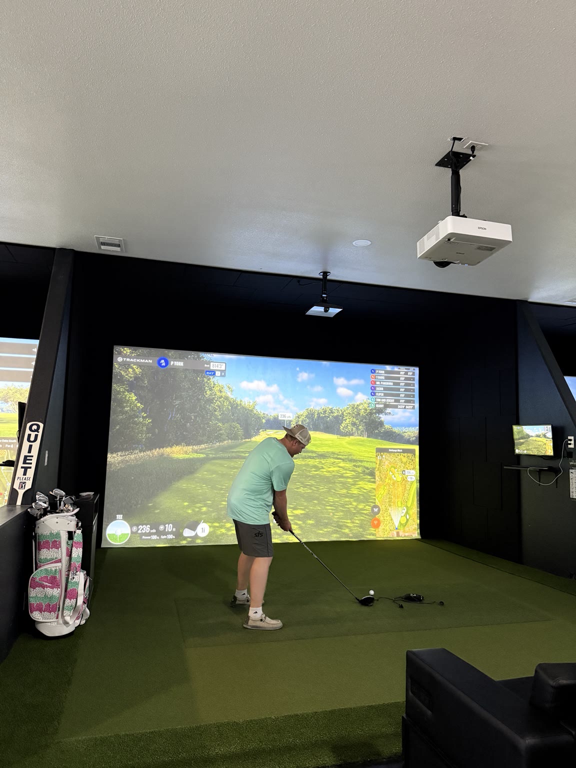 Golfer at the top of the backswing in a Virtual Tee simulator bay