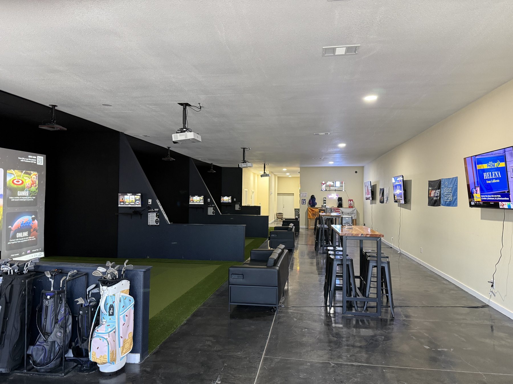 Three simulator bays with turf hitting areas and lounge seating at The Virtual Tee